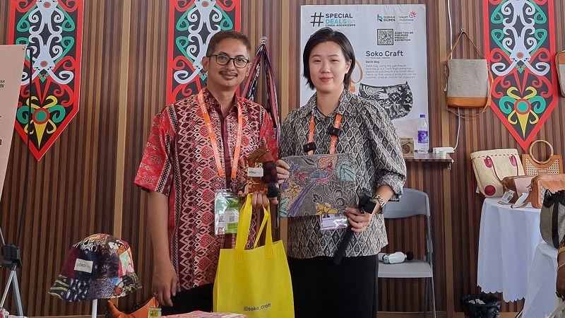 Manager Digitalisasi & Monetasi UMK Telkom, Achmad Retno Syafarie (kiri) bersama pengunjung yang membeli produk batik bag dari Soko Craft Pekalongan dalam gelaran China-ASEAN Expo di Nanning International Convention and Exhibition Center (NICE), yang berlokasi di kota Nanning, Guangxi, China beberapa waktu lalu. Soko Craft Pekalongan menjadi salah satu dari tiga UMK unggulan binaan Telkom yang turut hadir dalam gelaran tersebut.