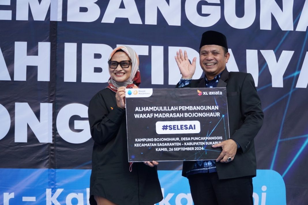 Presiden Direktur & CEO XL Axiata, Dian Siswarini (kiri) bersama Kepala Madrasah Ibtidaiyah Bojonghaur, Nanang Suryana (kanan) melakukan prosesi peresmian wakaf pembangunan Madrasah Ibtidaiyah Bojonghaur di Sukabumi, Kamis (26/9). Pembangunan ini meliputi renovasi ruang kelas, pondasi bangunan, lantai, pintu dan jendela. serta toilet. Selain itu juga dilakukan pembangunan ruang kelas baru, perpustakaan, serta pengadaan perlengkapan baru seperti meja dan bangku belajar, serta papan tulis.