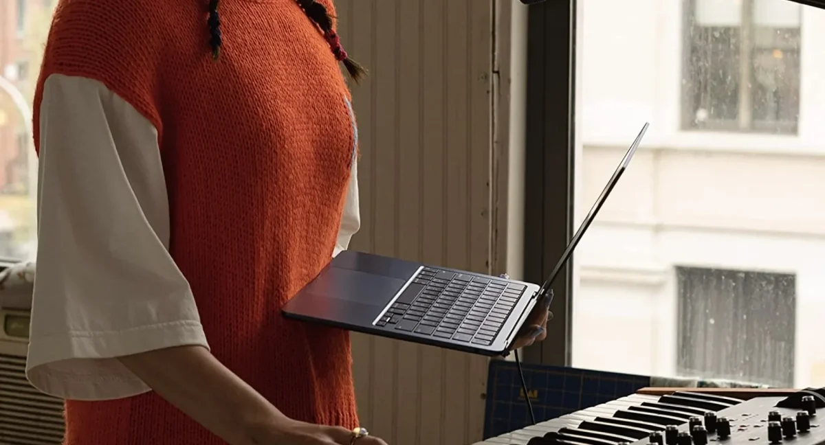 person holding m2 macbook air in front of piano