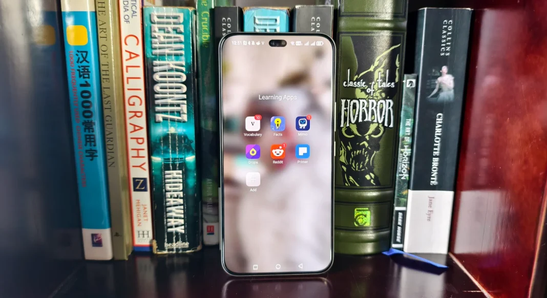 Folder aplikasi belajar di smartphone dengan latar belakang buku