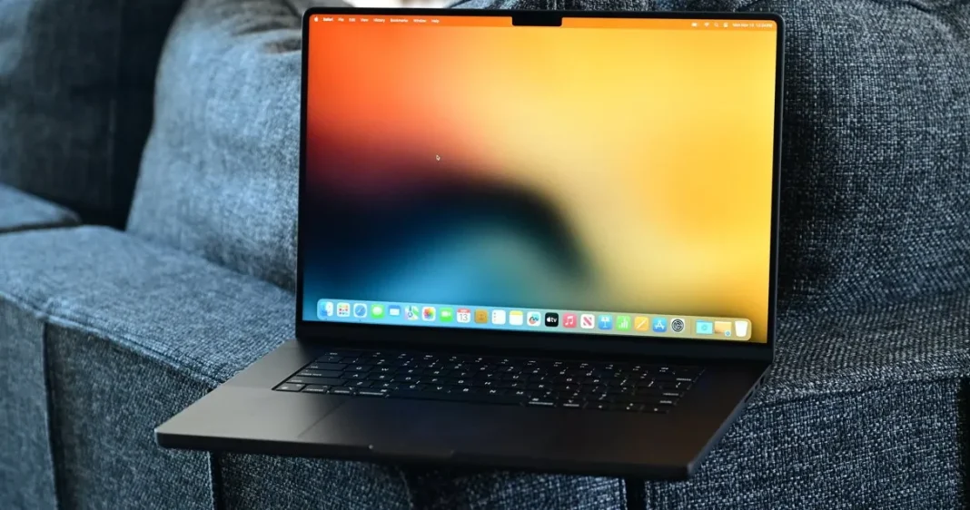 Laptop dengan layar berwarna-warni di atas sofa abu-abu