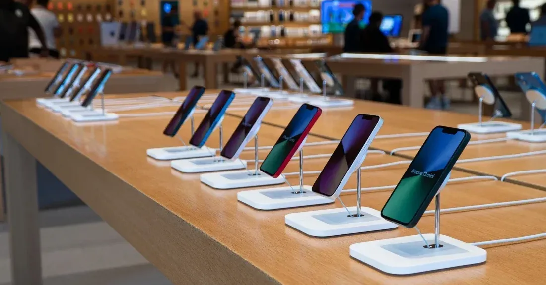 iPhones are lined up on a table at an Apple Store.