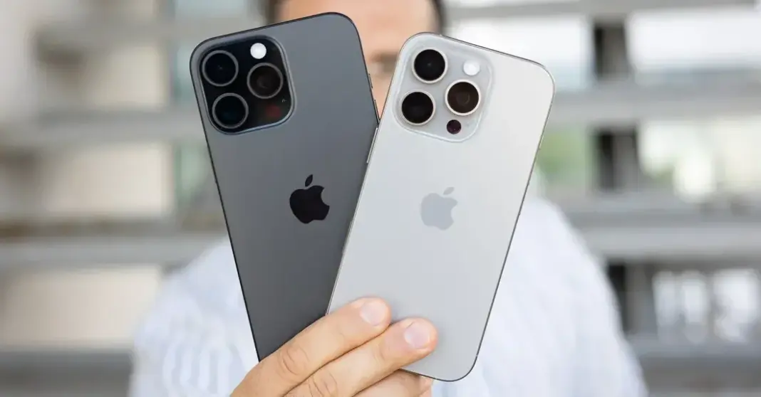Seorang pria memegang dua iPhone di depan toko Apple