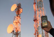 Pekerja memperbaiki pemancar sinyal internet di menara BTS