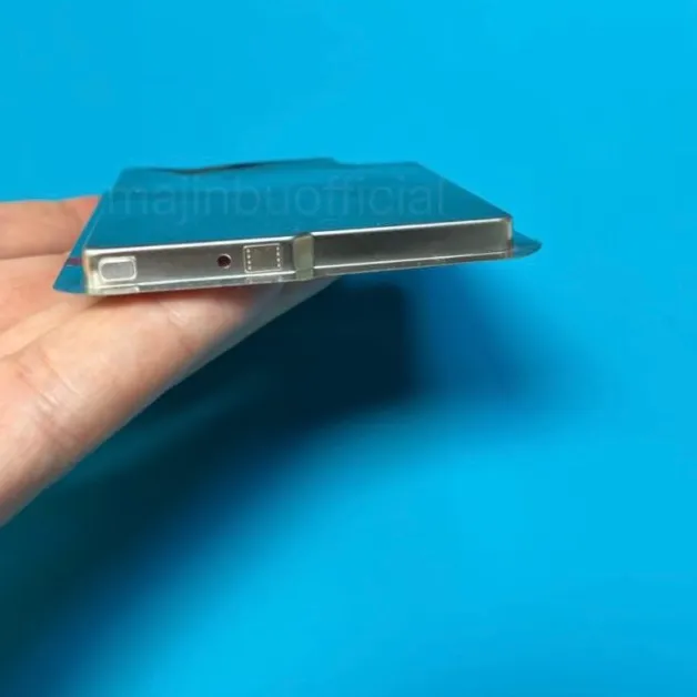 Person holding a sleek smartphone prototype with metal edges on a blue background.