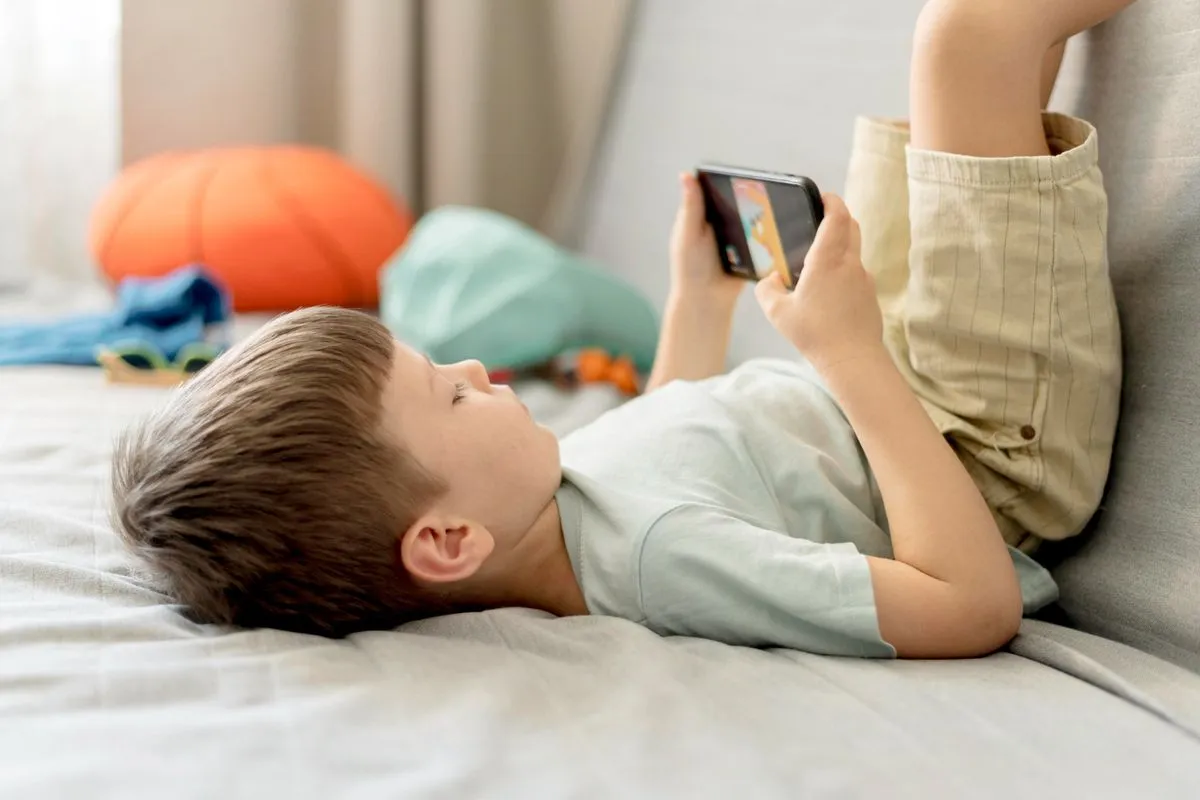 Ilustrasi anak main gadget sebelum tidur. Orang tua disarankan aktif memantau gim online anak dengan memilih sesuai usia, membatasi durasi main, dan memahami fitur interaktif agar anak tidak kecanduan serta tetap berkembang secara sehat.
