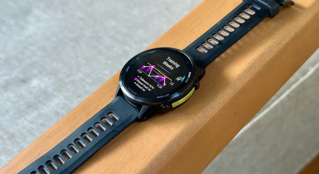 The Garmin Forerunner 970 sitting on an armrest showing the Training Weeks widget with running tolerance and impact load.