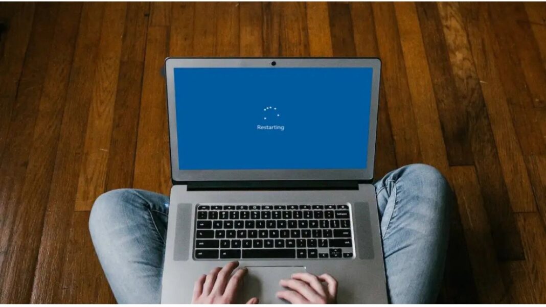 Ilustrasi laptop yang sedang restart dengan latar belakang diagram troubleshooting hardware dan software