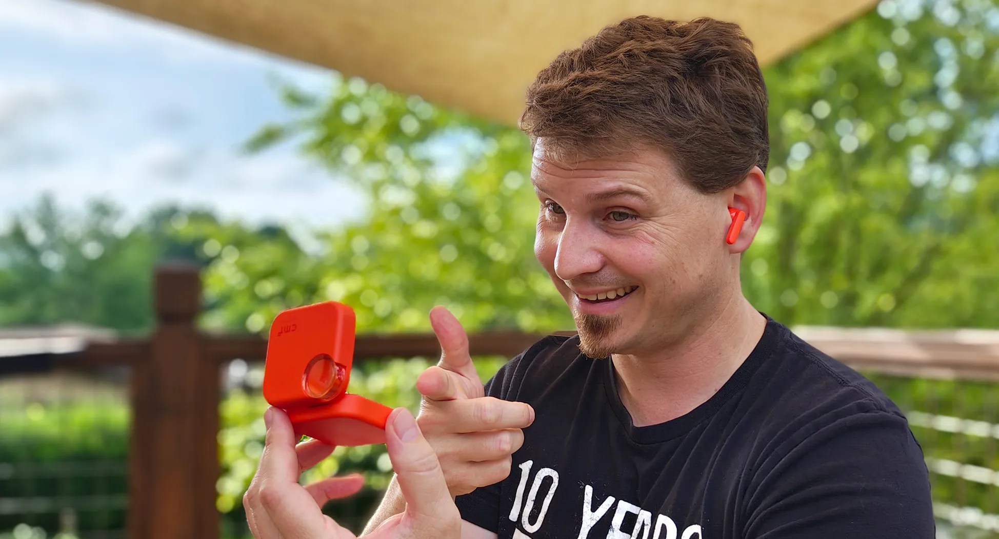 Wearing an orange CMF Buds 2 earbud and holding the case