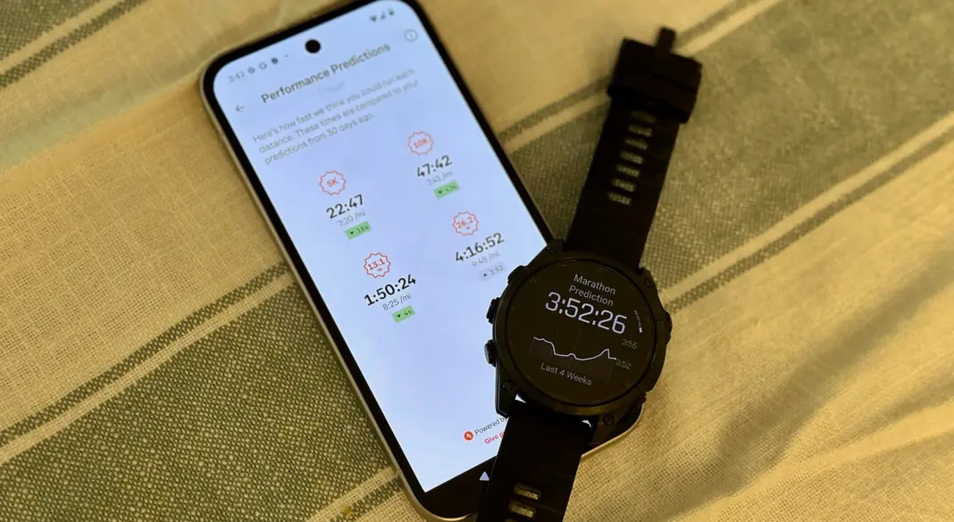 Tampilan aplikasi Strava yang menunjukkan prediksi performa lari dengan jam pintar Garmin Fenix 8 di latar belakang