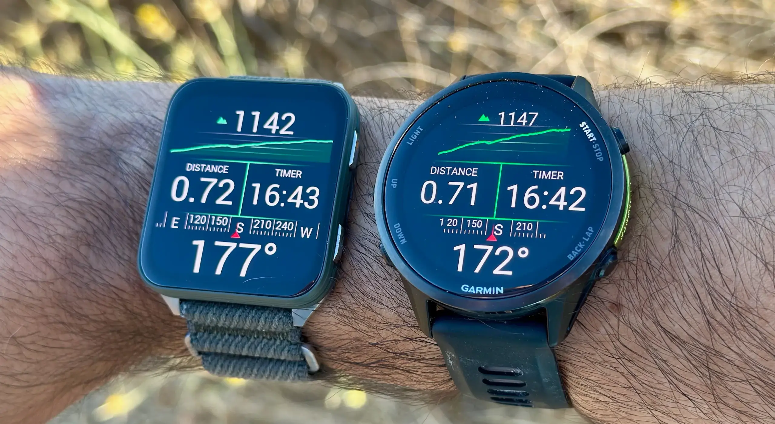 The Garmin Venu X1 (left) and Garmin Forerunner 970 (right), both on one wrist, showing near-identical stats for a hike activity's distance, time, elevation gain, and compass direction.