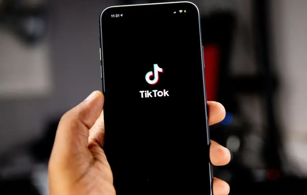 Ilustrasi aplikasi TikTok di smartphone dengan ikon koin dan gift, merepresentasikan sistem monetisasi platform