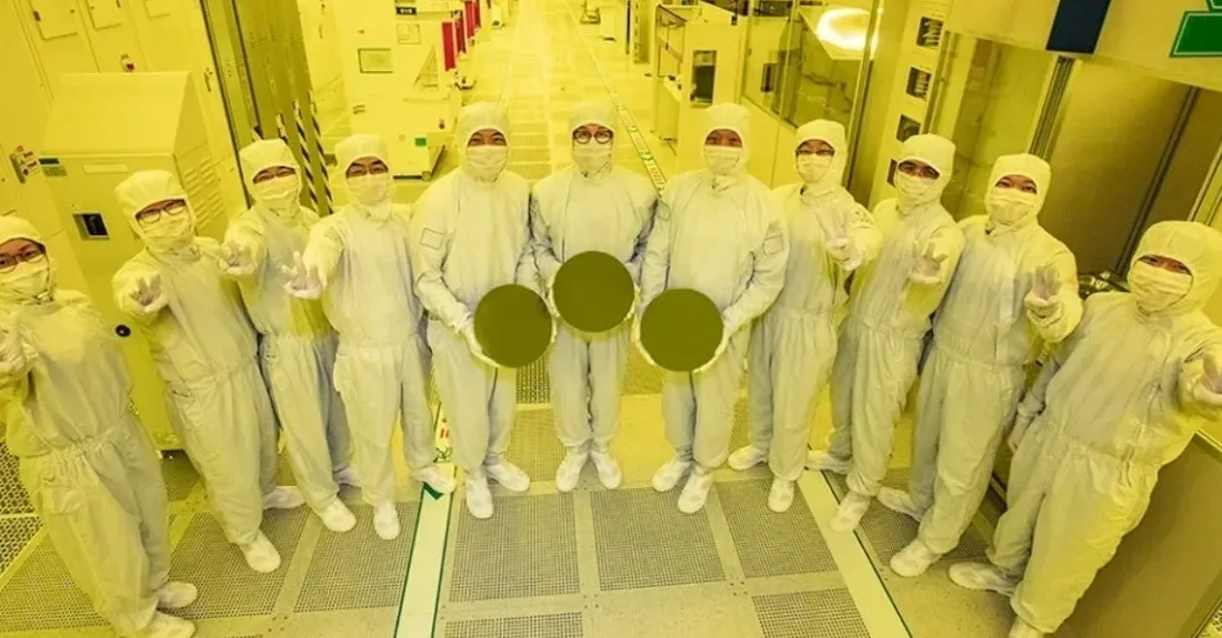 Foundry workers bathed in the yellow lighting in a cleanroom.