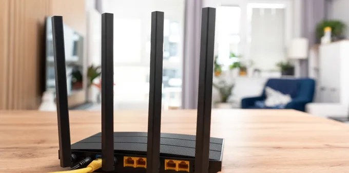 Black router with four antennas placed on a wooden table