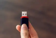 Tangan memegang USB flash drive dengan latar belakang abstrak, simbol pemanfaatan kreatif perangkat penyimpanan lama