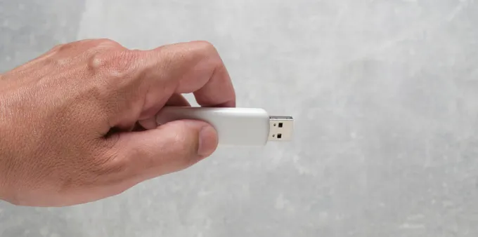 A hand holding a USB flash drive