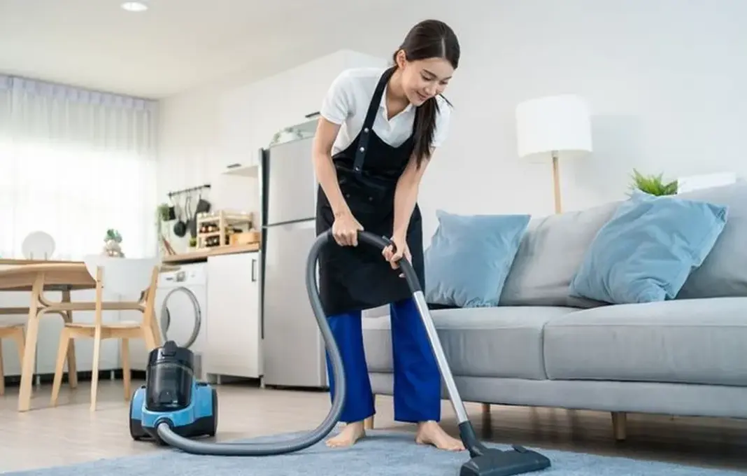 Ilustrasi vacuum cleaner modern sedang menyedot debu di lantai rumah