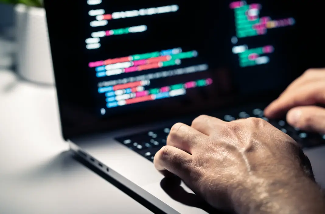 Hacker dengan kode malware di layar komputer menunjukkan serangan siber dan keamanan cyber