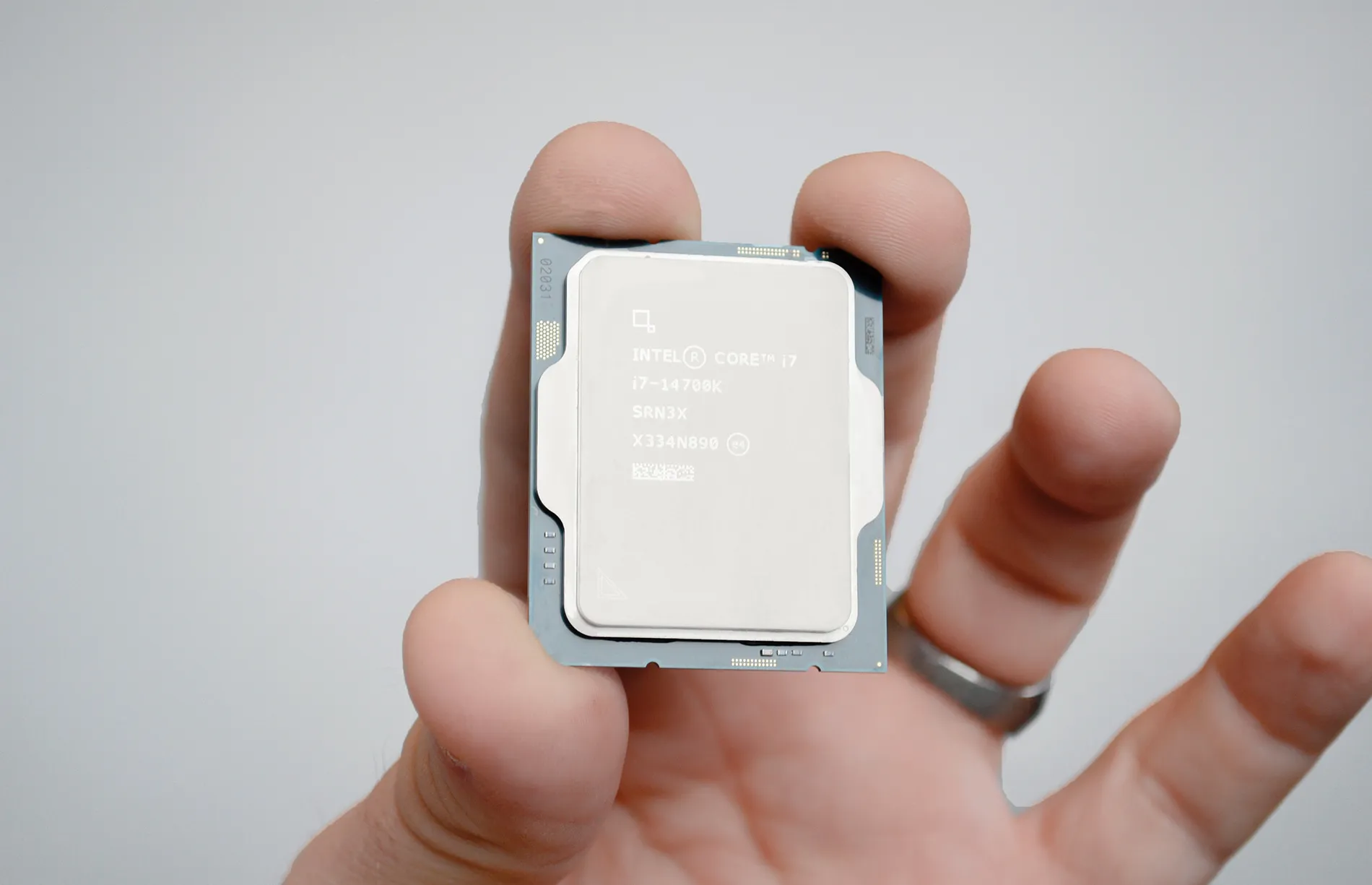 A masculine hand holding an Intel Core i7-14700K