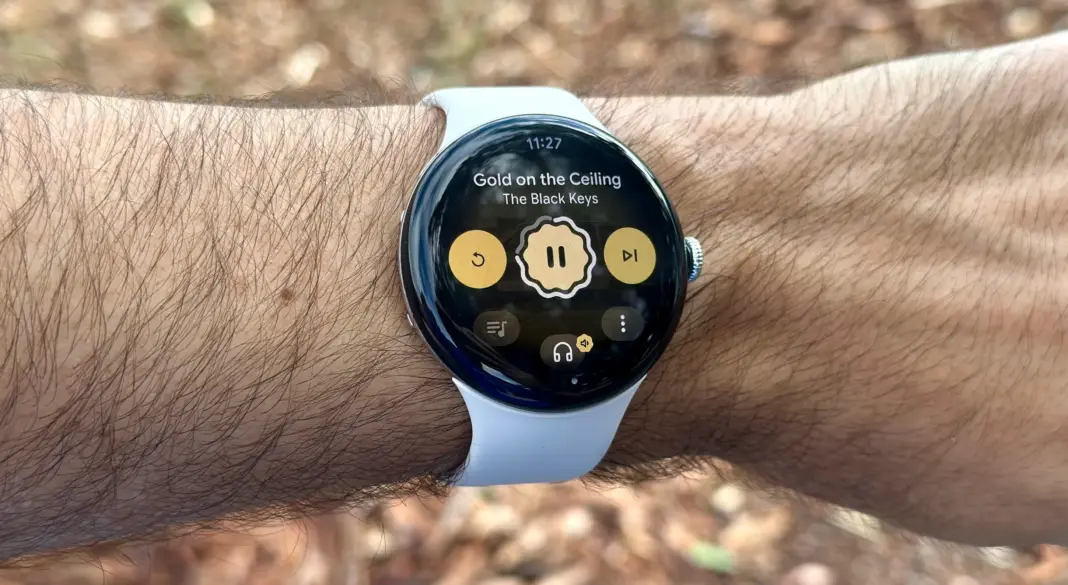 Google Pixel Watch 4 di pergelangan tangan dengan tampilan kontrol musik Pandora di luar ruangan
