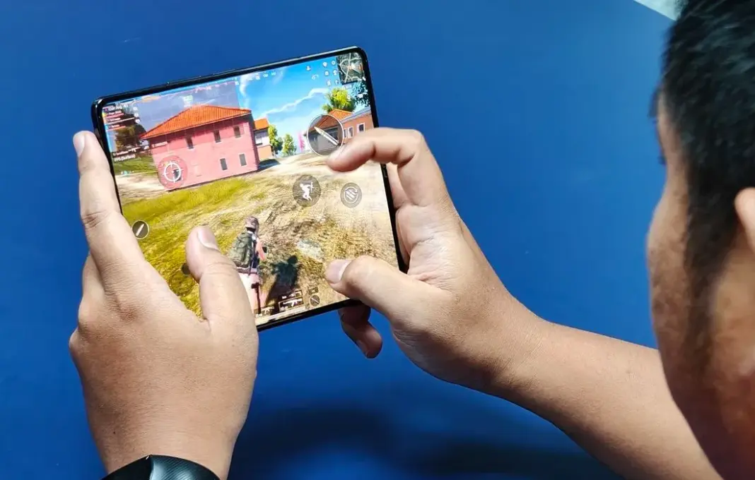Ilustrasi bermain game PUBG Mobile di smartphone dengan latar belakang grafis game yang menampilkan karakter dan senjata