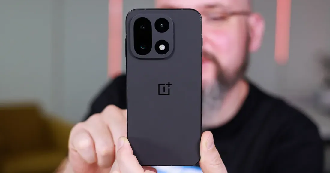 A man holding a black OnePlus 15.