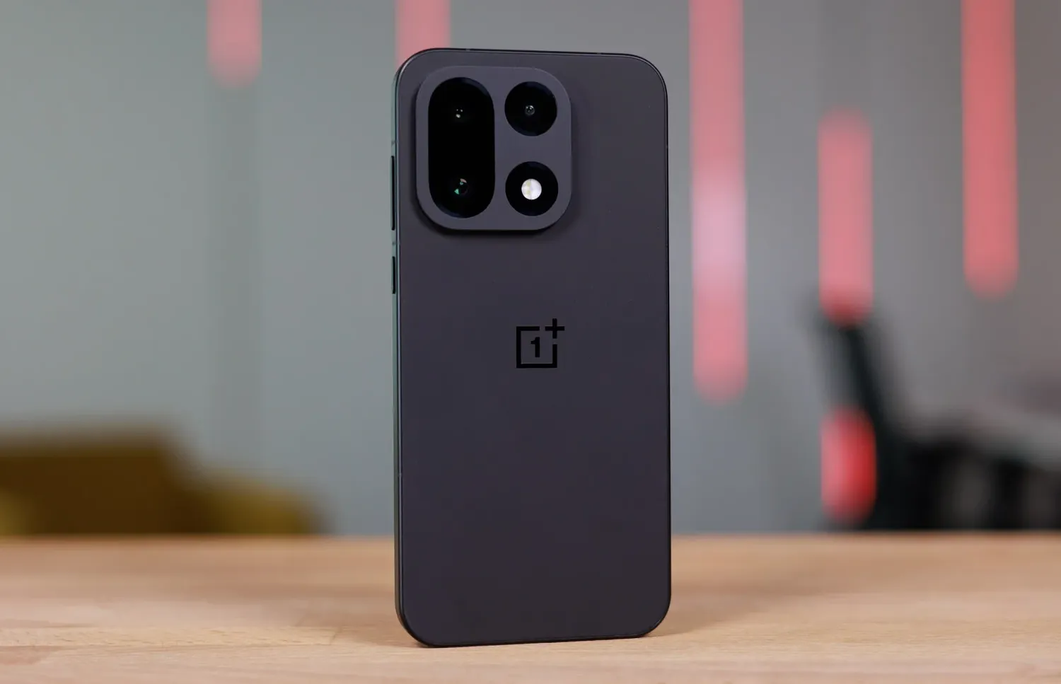 A black OnePlus 15 placed on a wooden table.