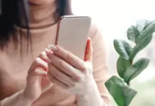 Kirim Stiker Presiden di WhatsApp Bakal Kena Pidana, Ini Kata Menkum Wanita muda memegang smartphone dan melihat layar ponsel dengan ekspresi serius