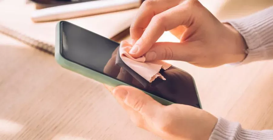 Proses membersihkan layar smartphone dengan kain microfiber