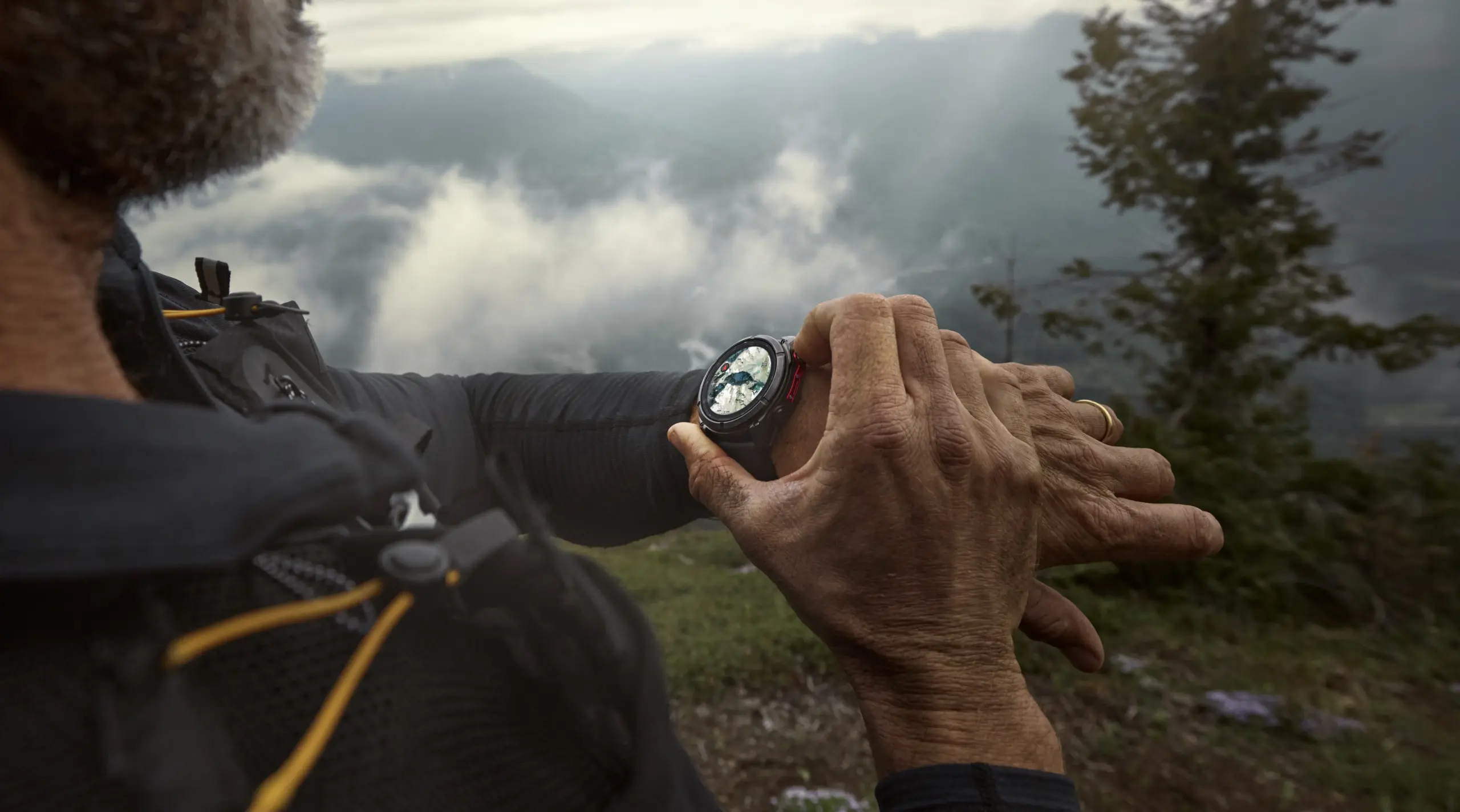 A photo of a man in the mountains wearing a Garmin Fenix 8 Pro, using it to check his nearby mapped location.