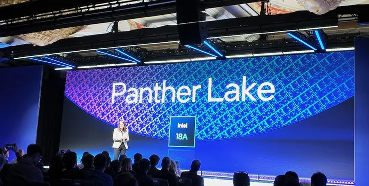 A photograph of Intel's Interim Co-CEO Michelle Johnston Holthaus standing on stage, with a background displaying Panther Lake and Intel 18A