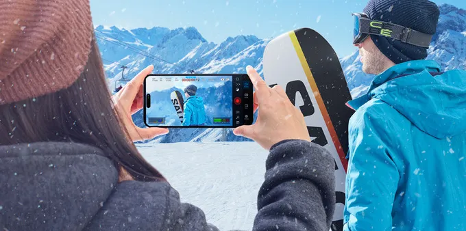 A person using the Blackmagic Camera app to record a snowboarder