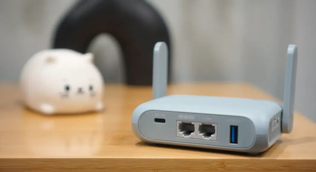 Router travel GL.iNet Beryl AX diletakkan di atas meja kayu sebagai ilustrasi perangkat jaringan portabel.