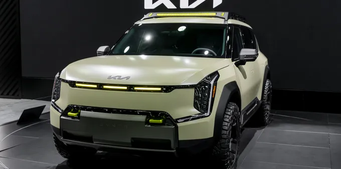 A green Kia EV9 a black backdrop.