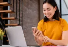 Wanita muda menggunakan ponsel dan laptop untuk mempersiapkan pembelian tiket konser online (cara war tiket konser) dengan serius.