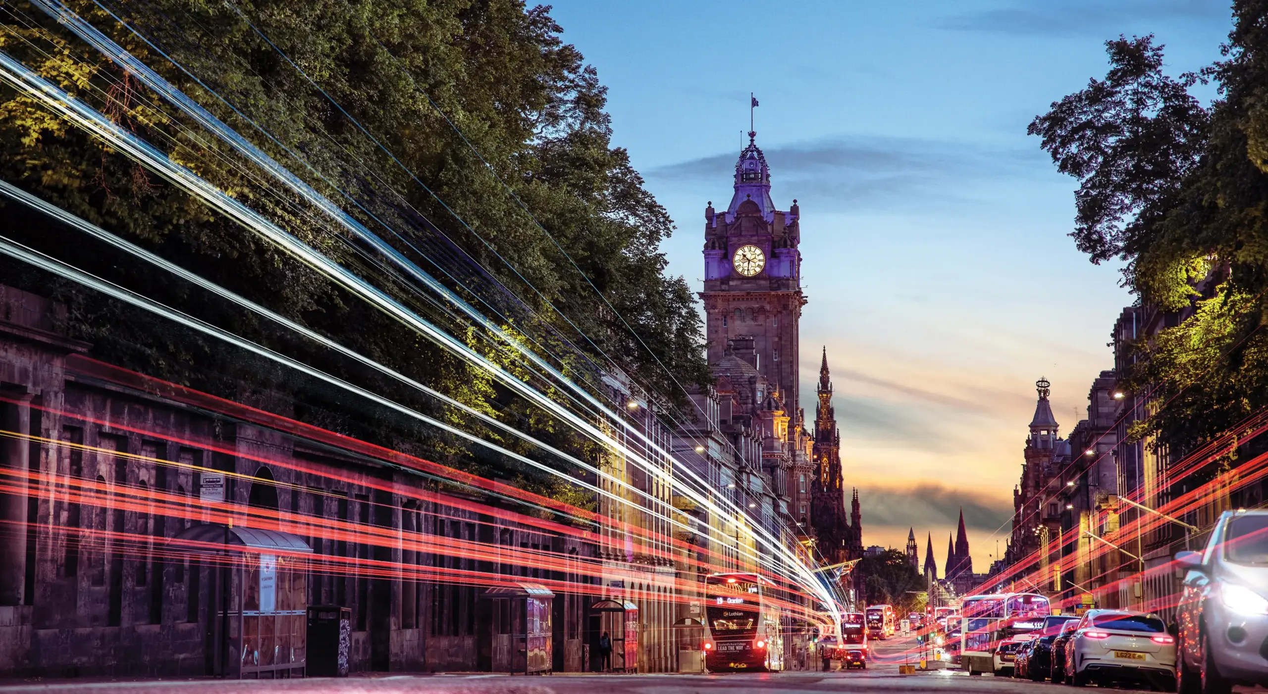 An evening image of Princes Street in Edinburgh, at sunset, with light trails from passing traffic
